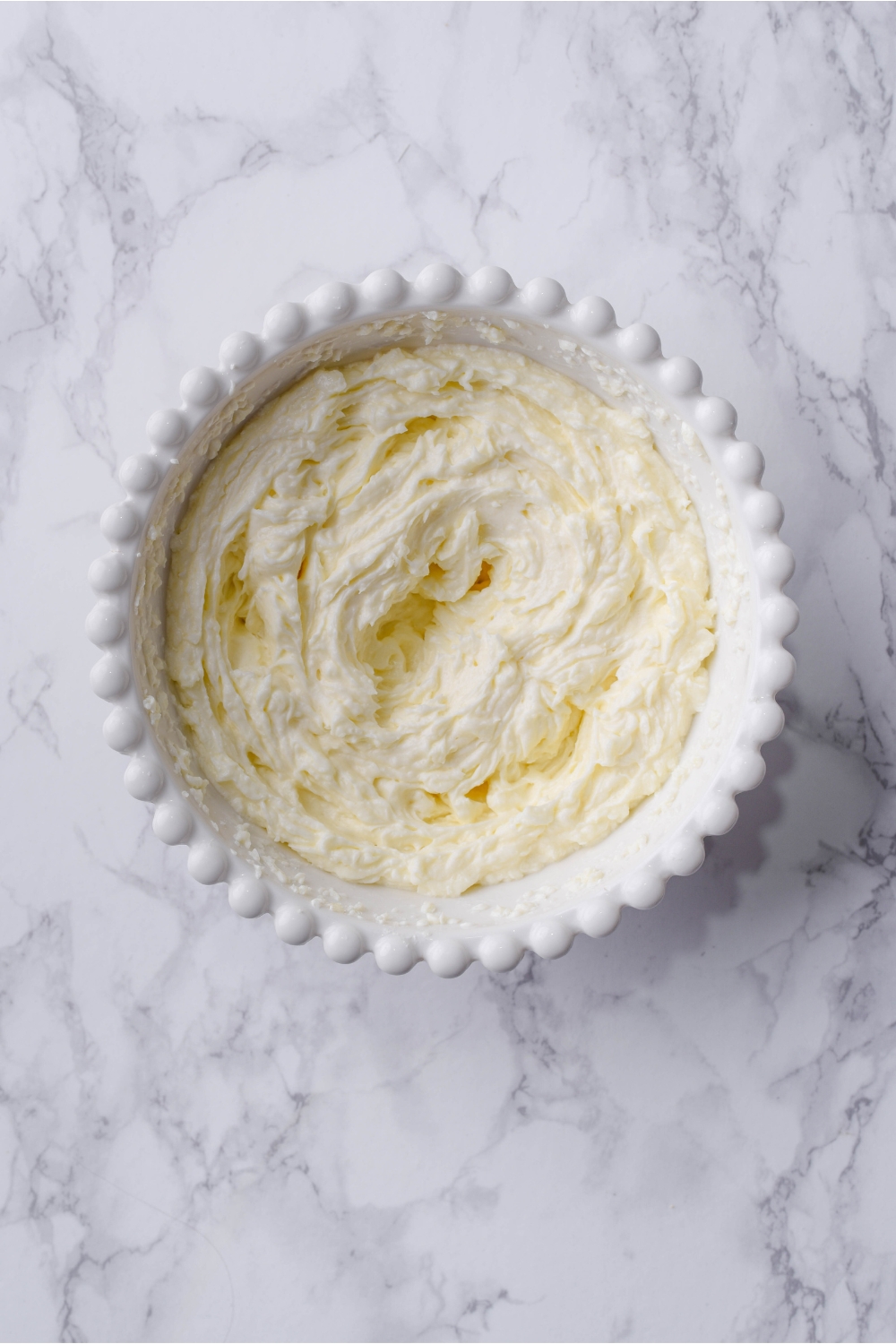 A white bowl filled with a softened cream cheese mixture.
