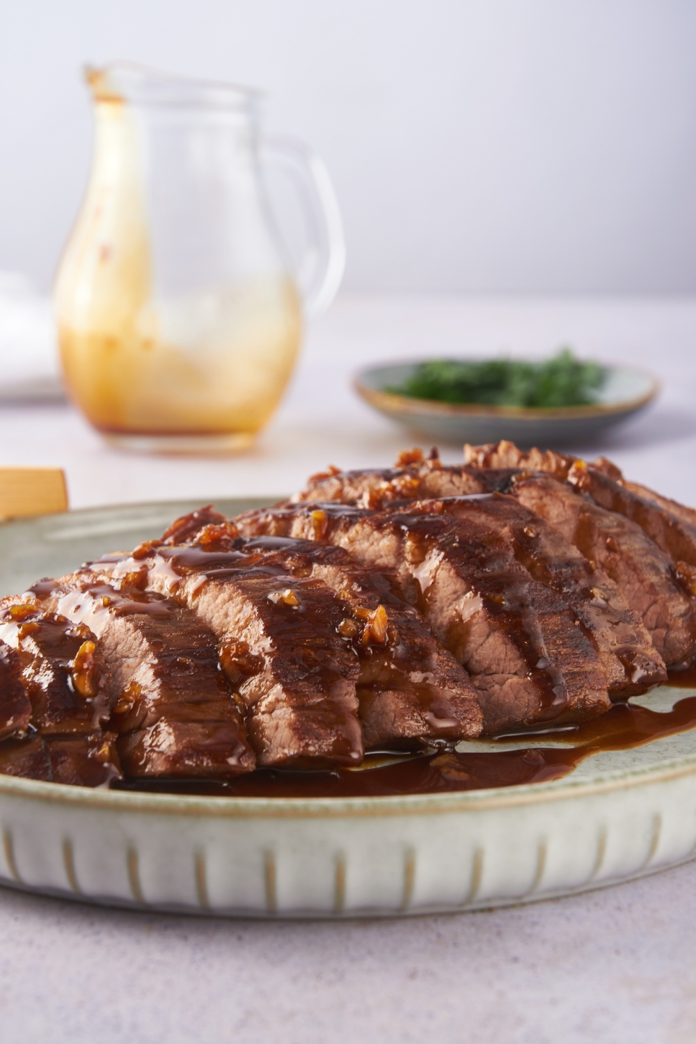 Close up of London broil sliced thin on a plate and covered in a soy sauce glaze.