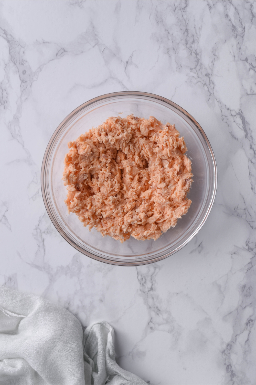 A clear bowl filled with minced canned salmon.