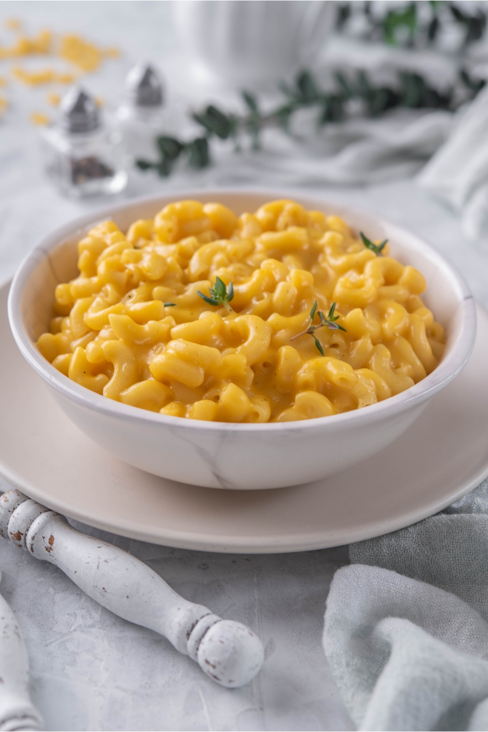 A bowl of creamy macaroni and cheese with fresh herbs garnished on top.
