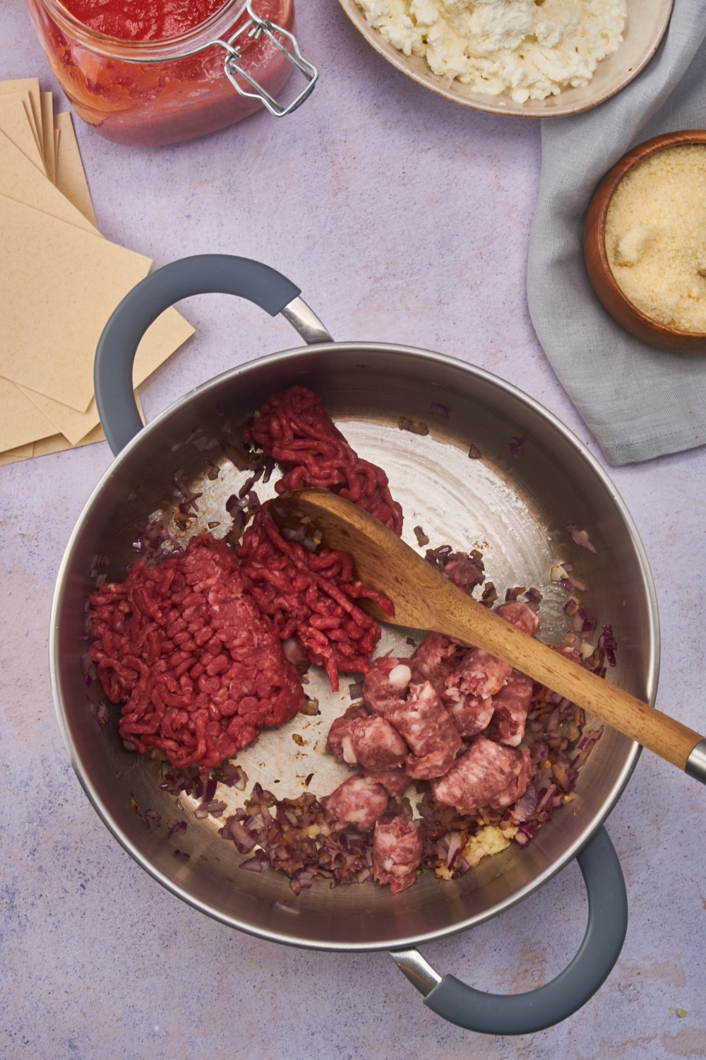 Large pot filled with raw ground beef and sausage crumbled but not combined.