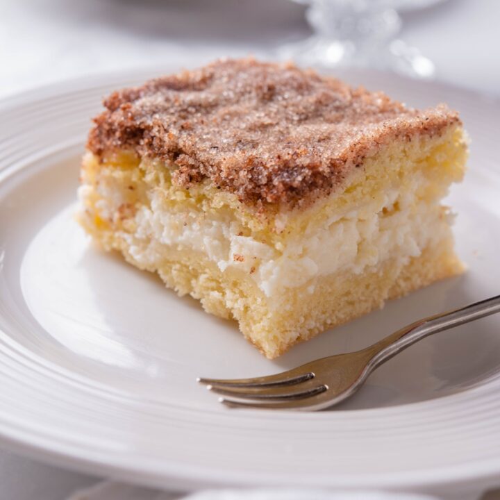 A square serving of sopapilla cheesecake with a small fork on the plate.