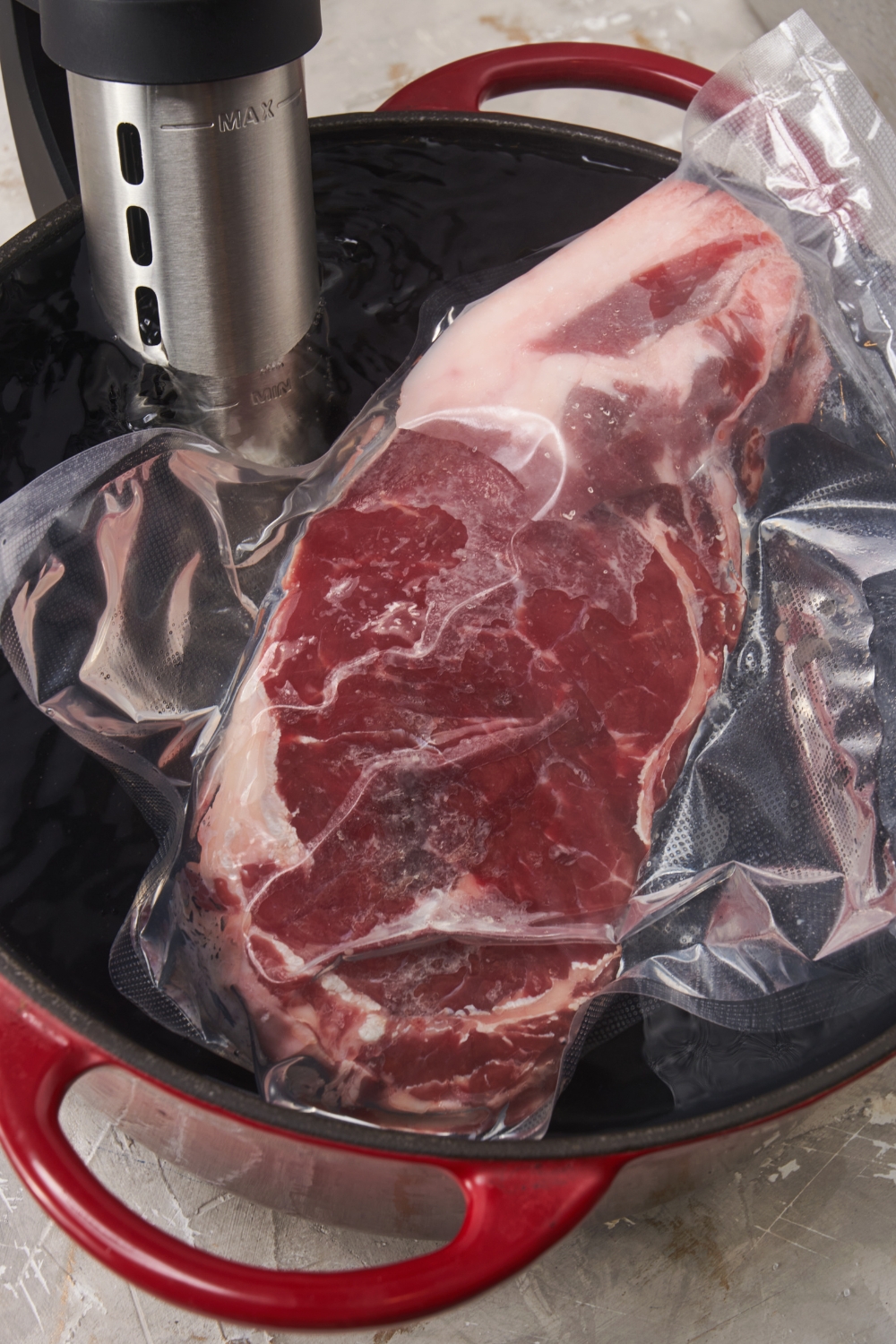 Prime rib in a vacuum sealed bag being cooked in a water bath with a sous vide cooker.