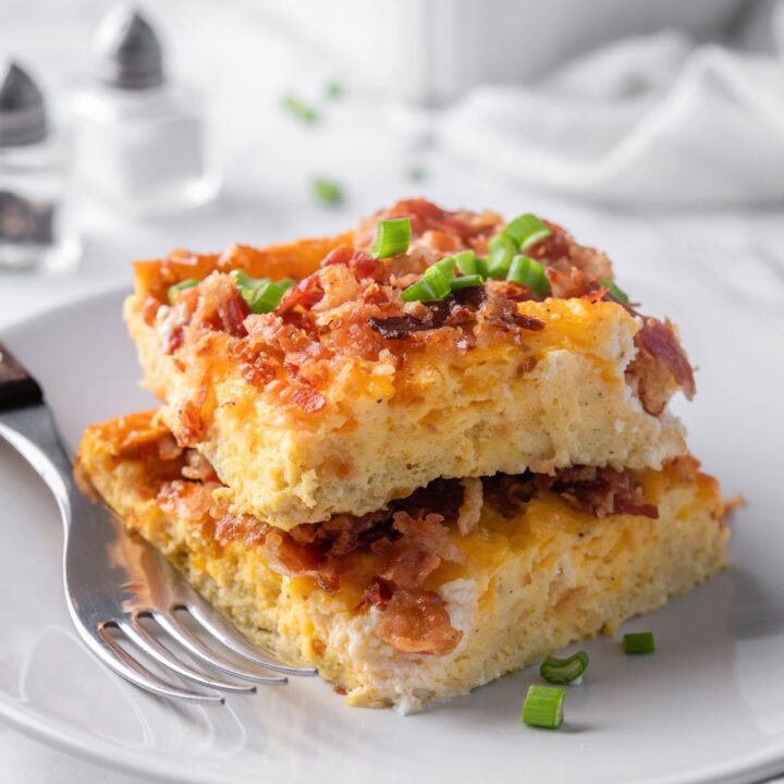 Two squares of a breakfast casserole with bacon on top of one another.