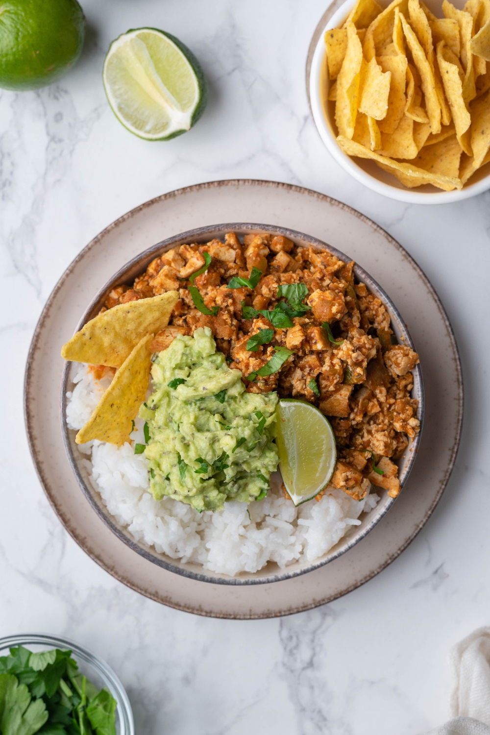 An overhead view of a bowl with chipotle sofritas served with rice and topped with guac and a lime wedge.