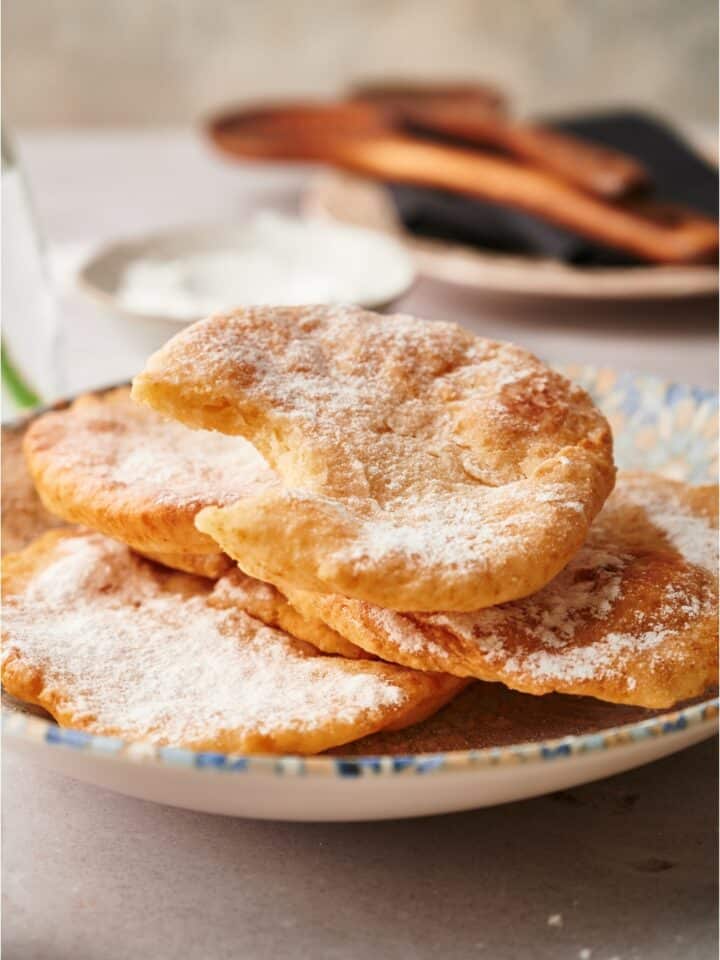 A piece of fried dough with a bite out of it on pieces of fried dough.