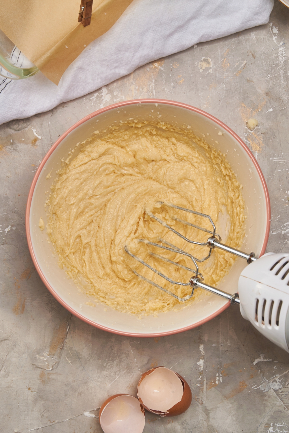 A mixing bowl with a handheld beater creaming the butter, sugar, and egg.