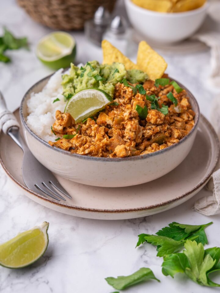 A bowl with chipotle sofritas served with rice and topped with guac and a lime wedge.