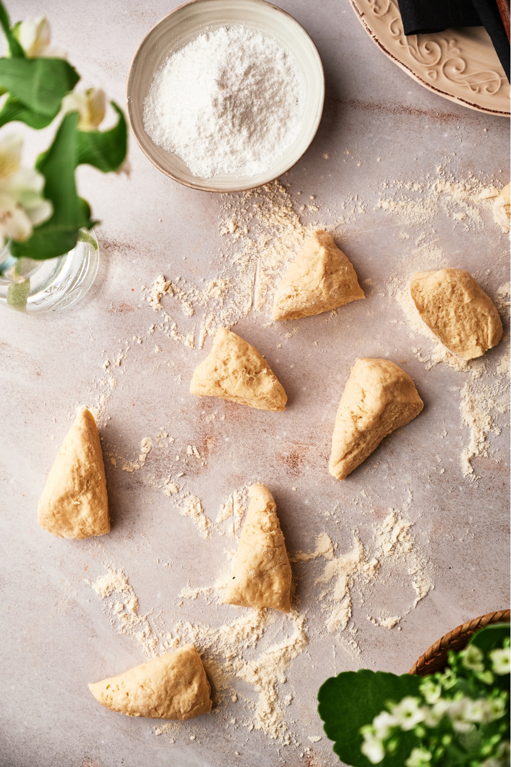 Seven triangle pieces of dough on a floured surface.