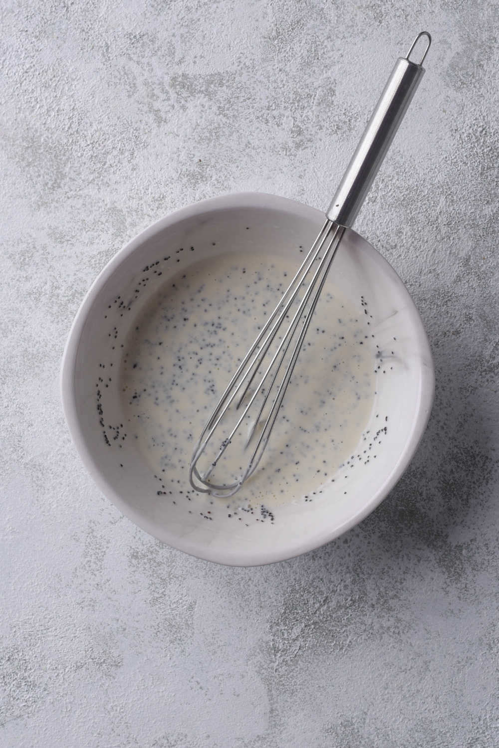 A small bowl with the poppyseed dressing ingredients mixed together to make a creamy dressing.