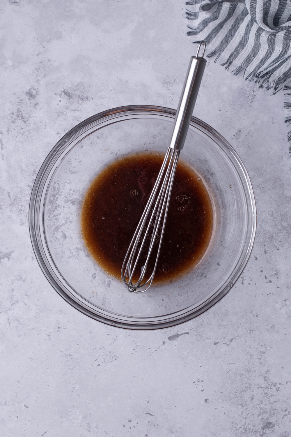 A mixing bowl with spicy sauce and a whisk.
