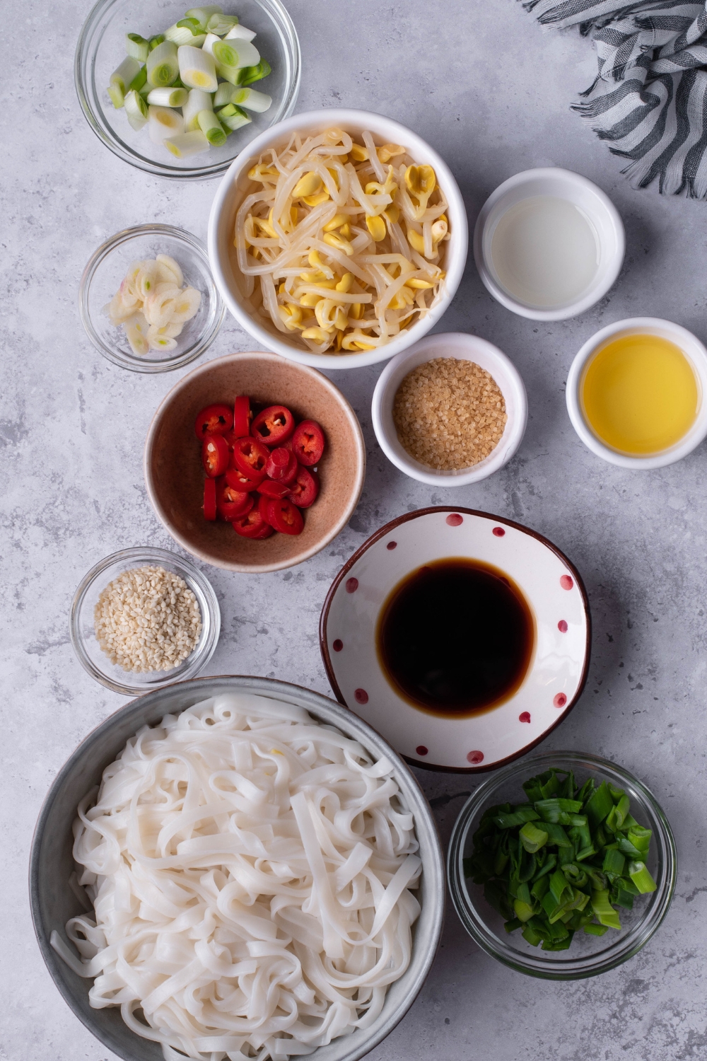 An overhead view of multiple bowls with the ingredients to make spicy noodles.