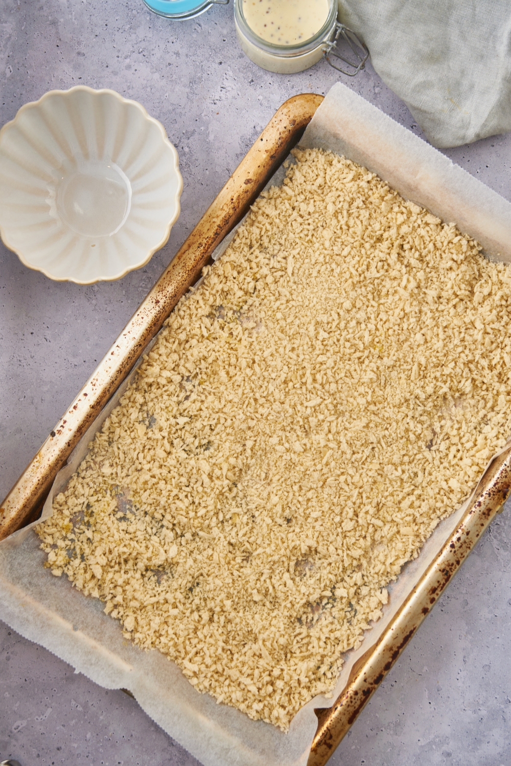 A baking sheet lined with parchment paper covered in an even layer of panko bread crumbs.
