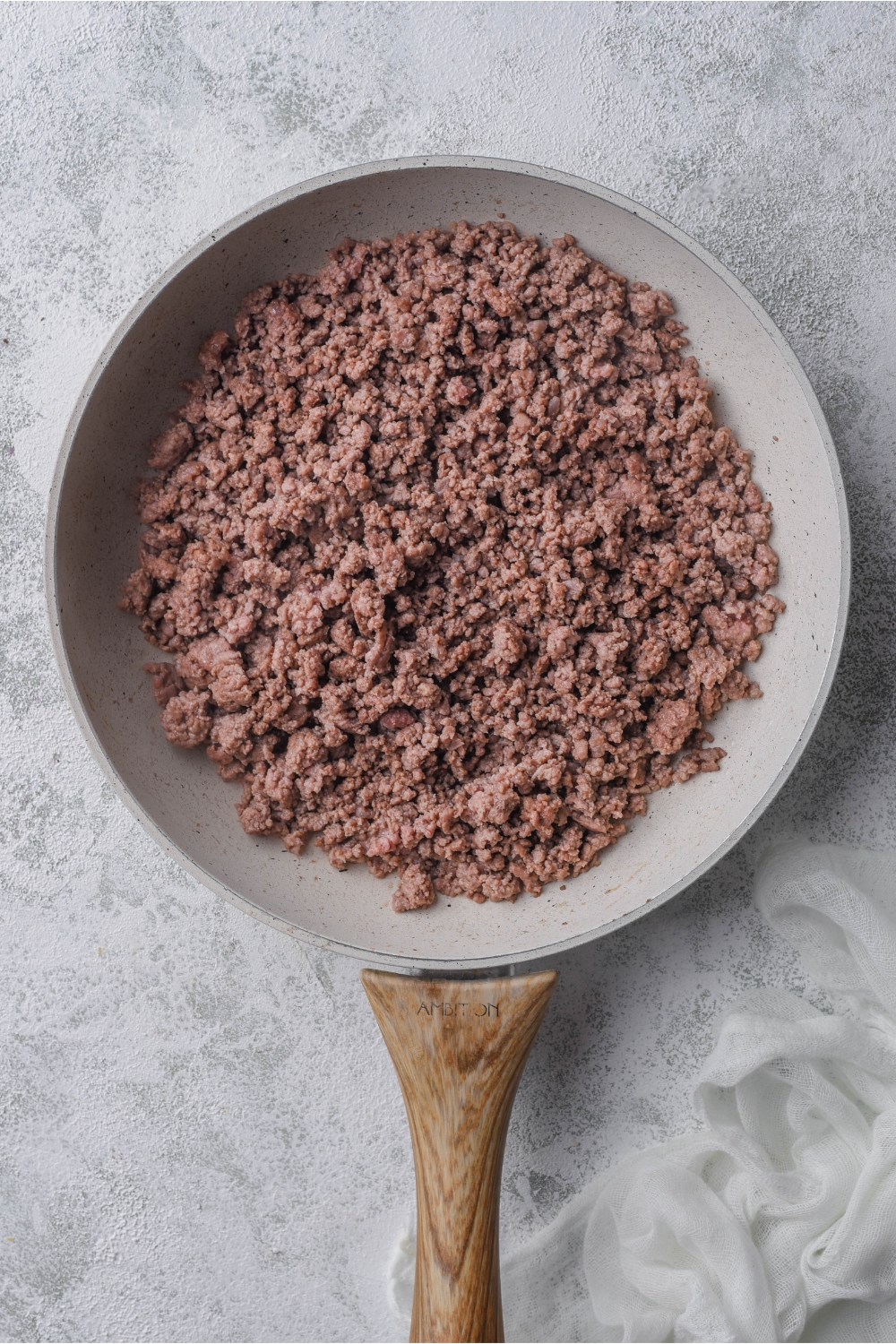 A frying pan with ground beef cooking.