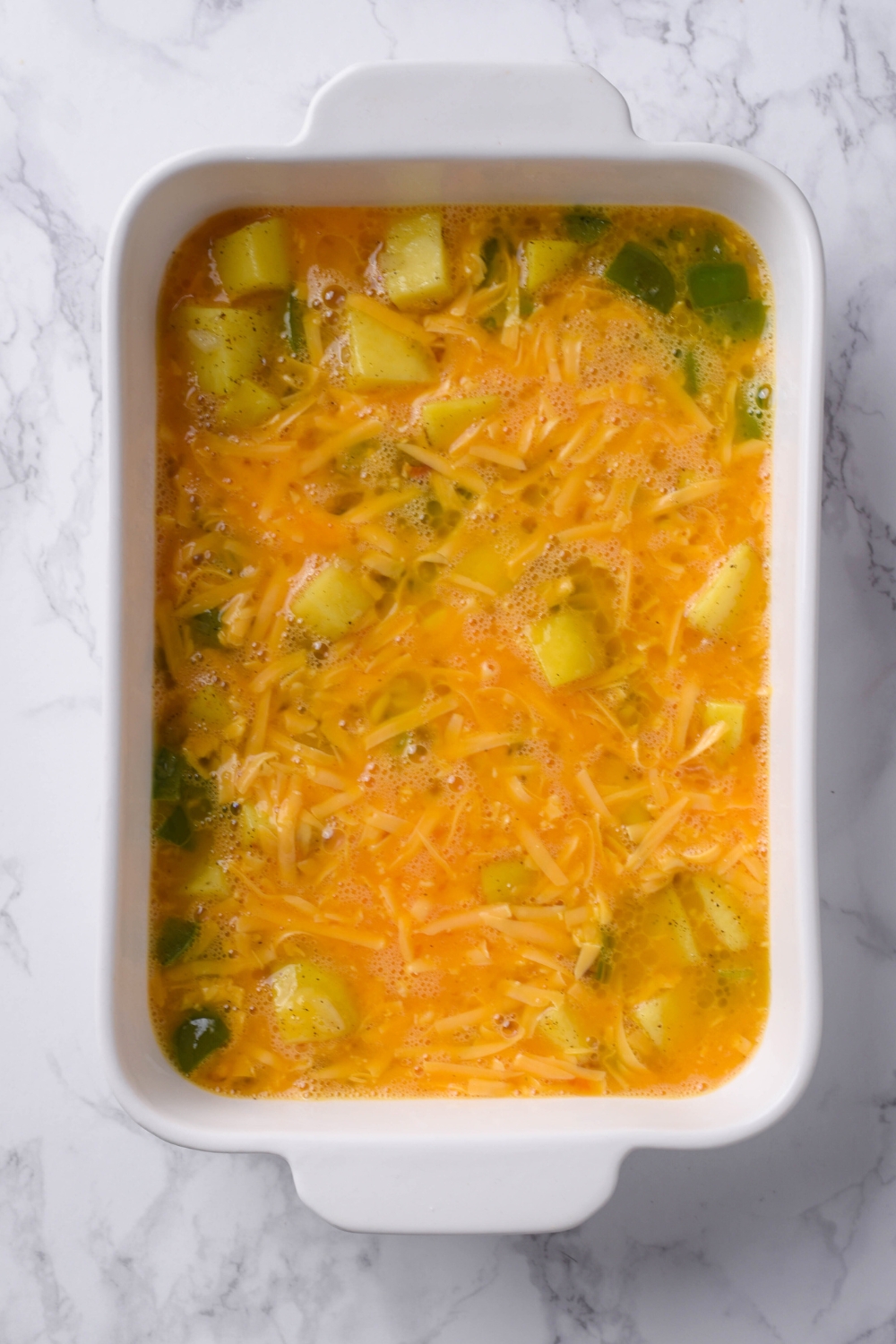 A casserole dish with uncooked potato casserole.