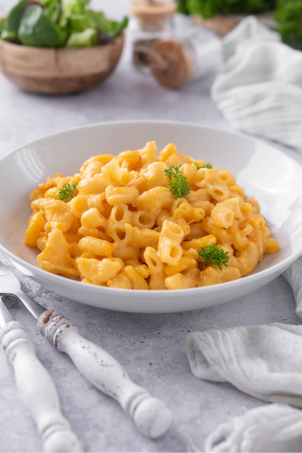 A bowl of mac and cheese garnished with bits of parsley.