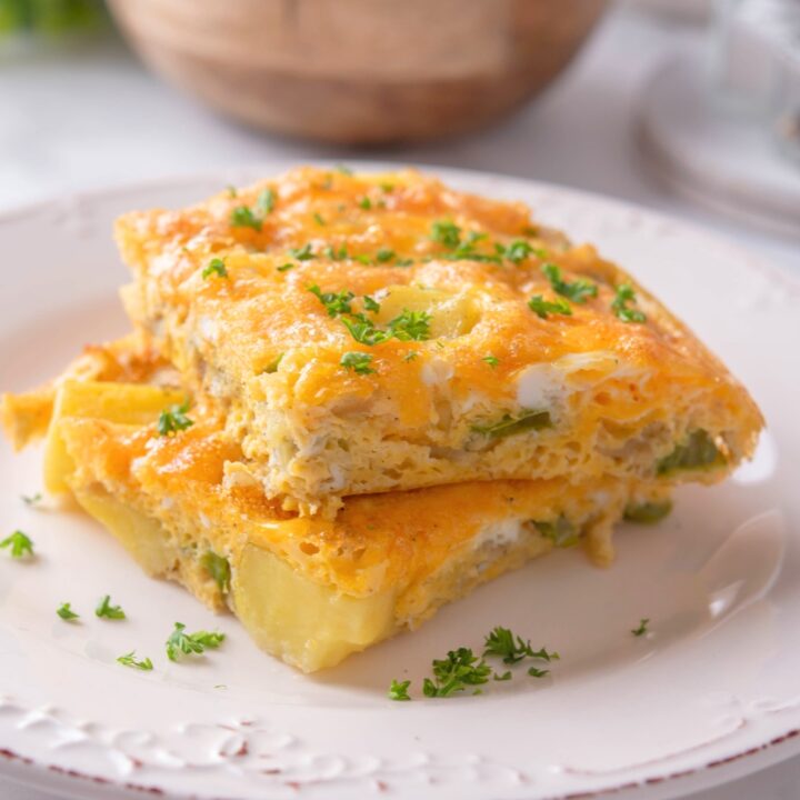 Two squares of potato egg casserole on top of one another on a white plate.