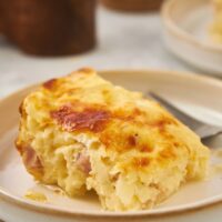 A slice of ham and cheese breakfast casserole on a plate.