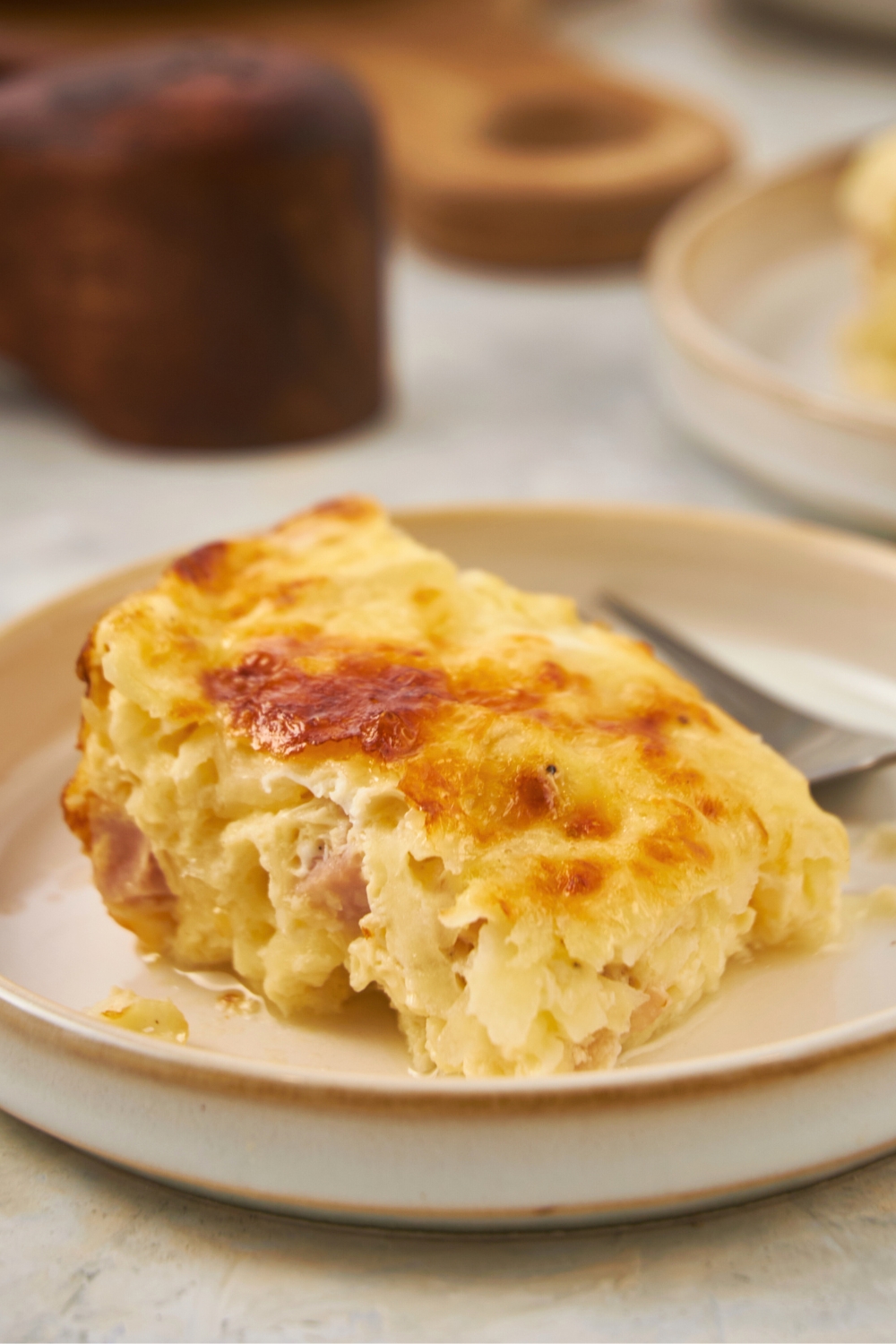 A slice of ham and cheese breakfast casserole on a plate.