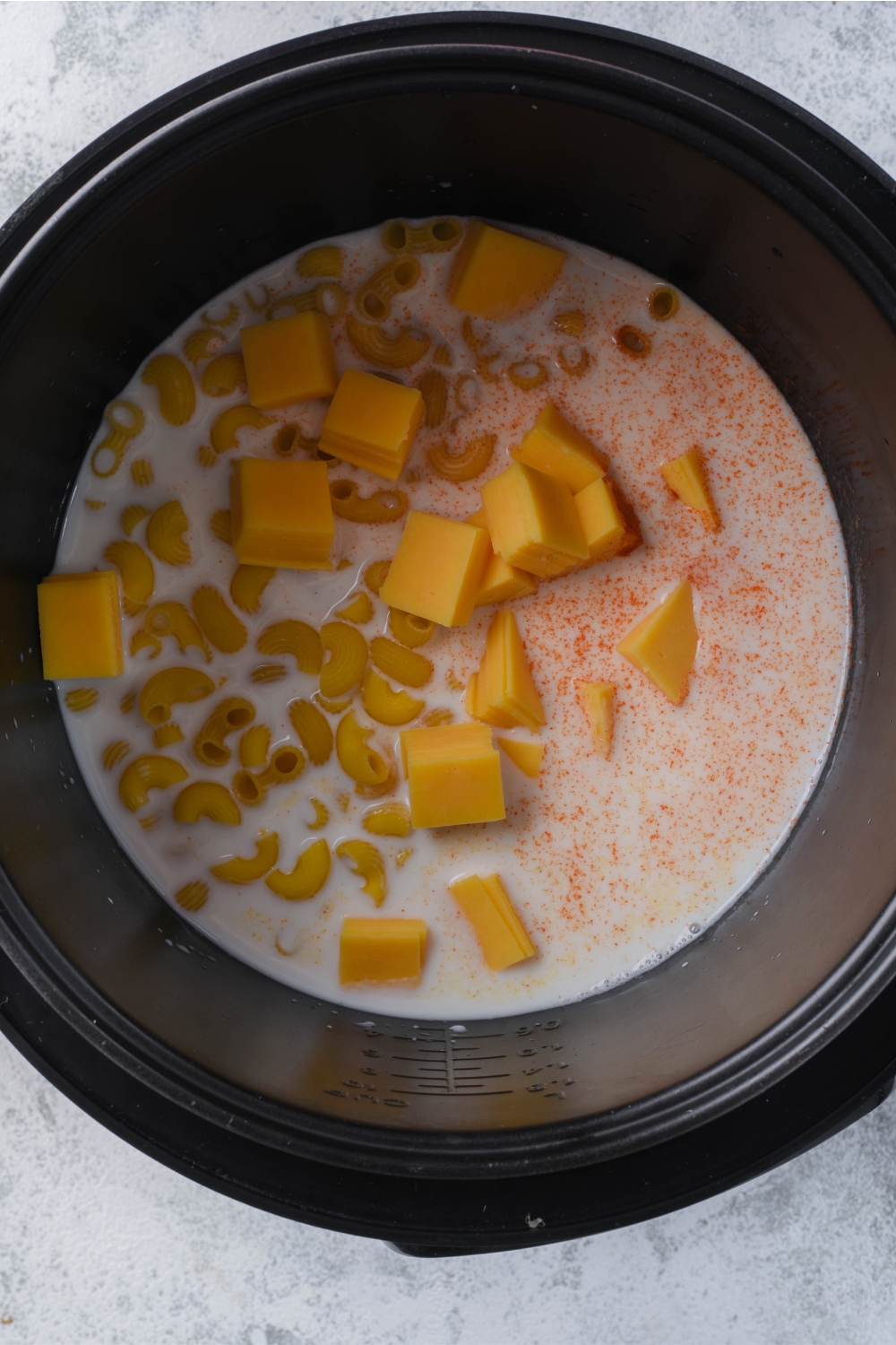 A crockpot with the ingredients to make homemade mac and cheese.