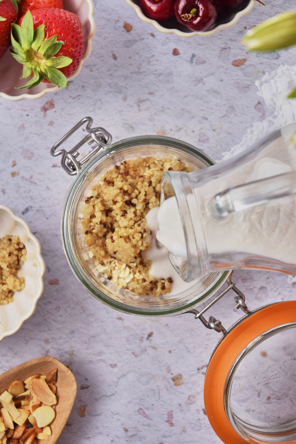 Coconut milk being poured into a mason jar filled with quinoa and oats.