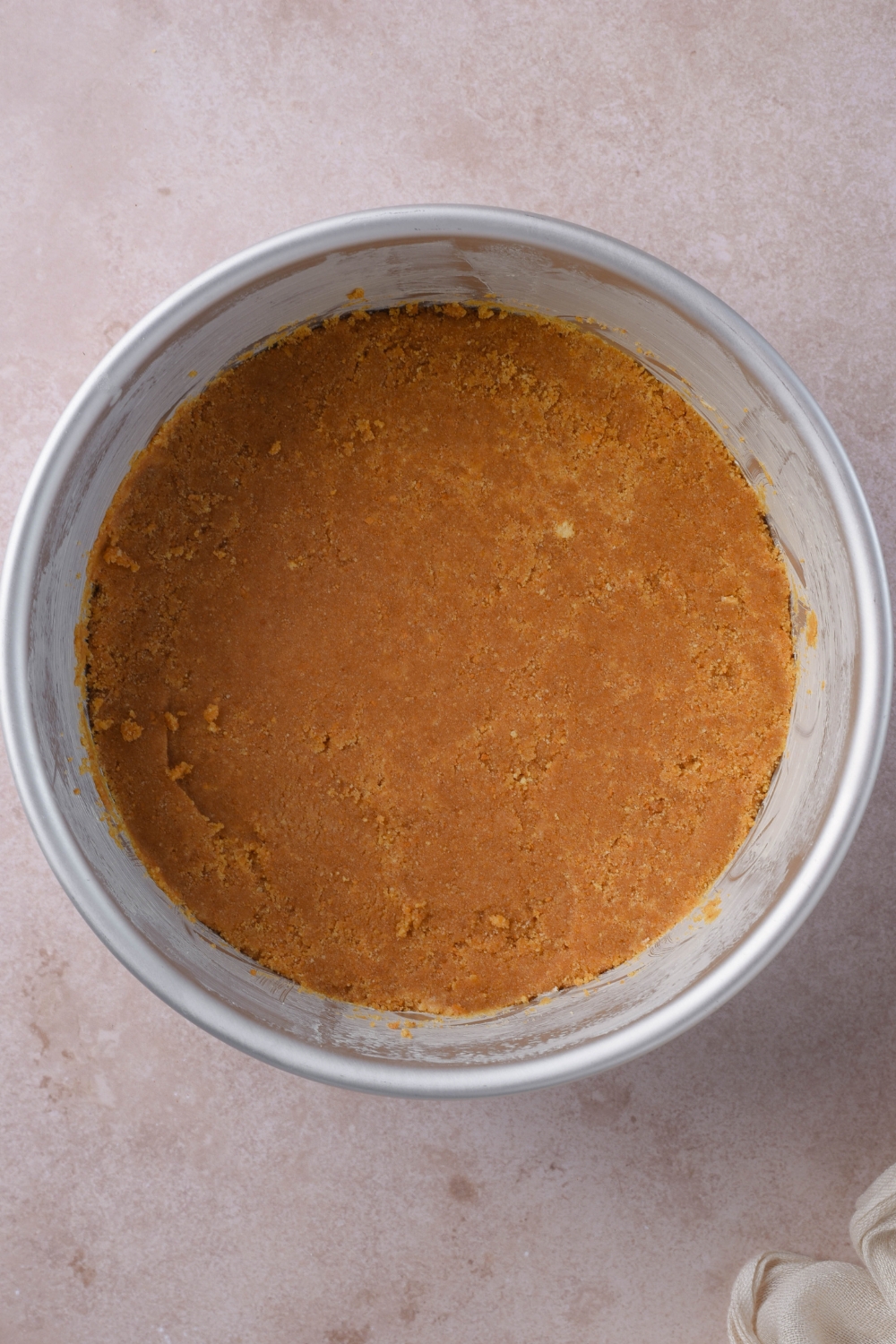 A springform pan with graham cracker crust on the bottom.