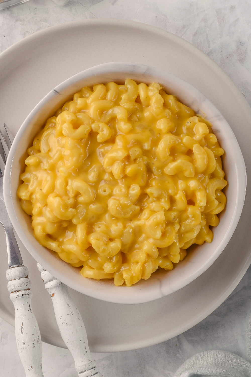 Mac and cheese in a white bowl on top of a white plate.