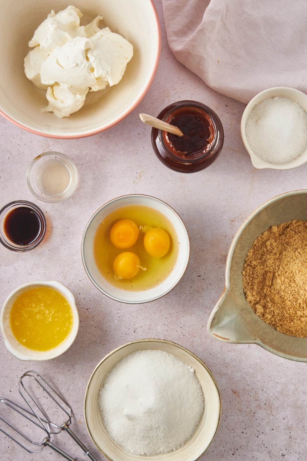 A countertop with the ingredients to make philadelphia cheesecake and graham cracker crust.