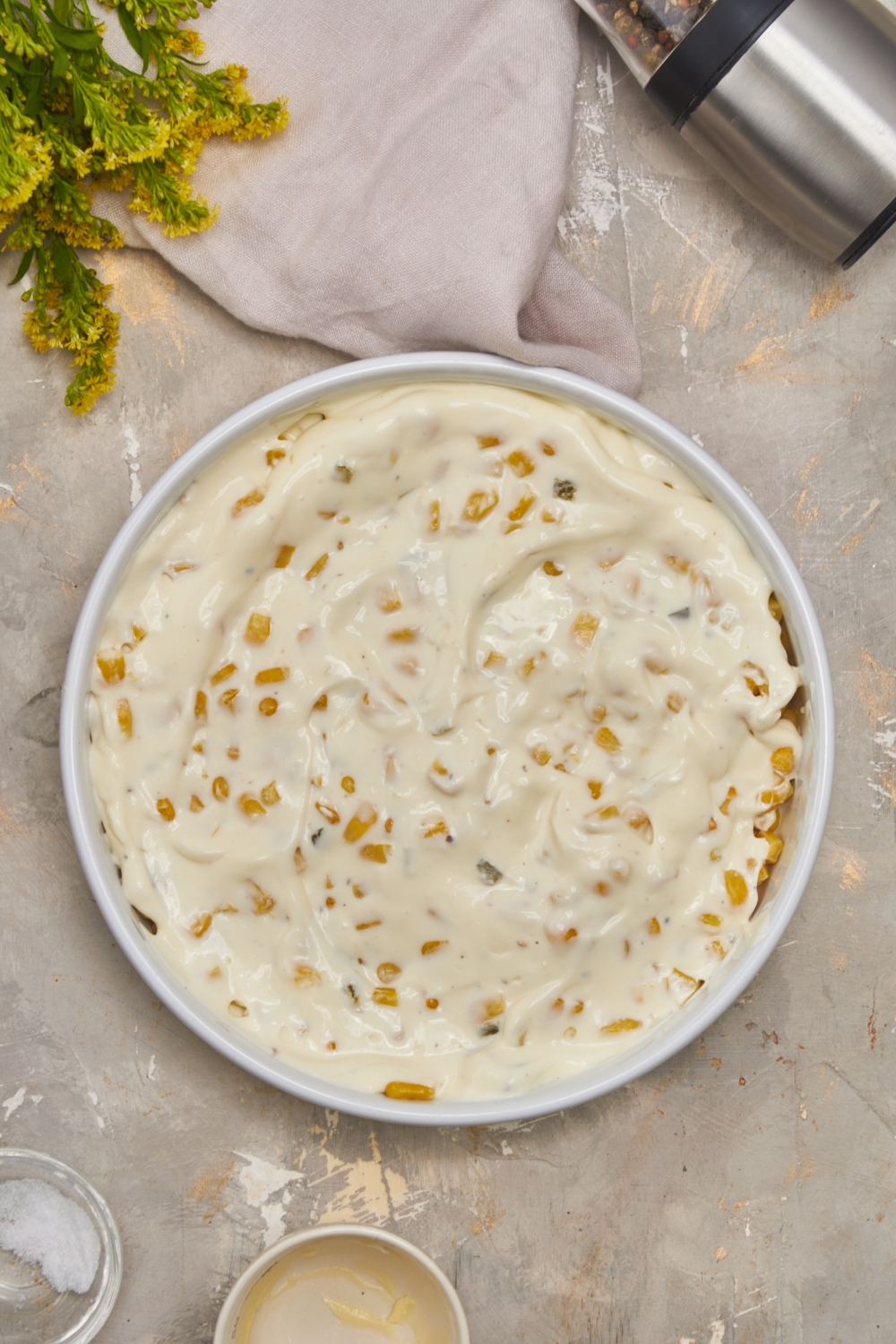 A round white baking dish filled with corn and a cream sauce mixture spread over top of the corn.