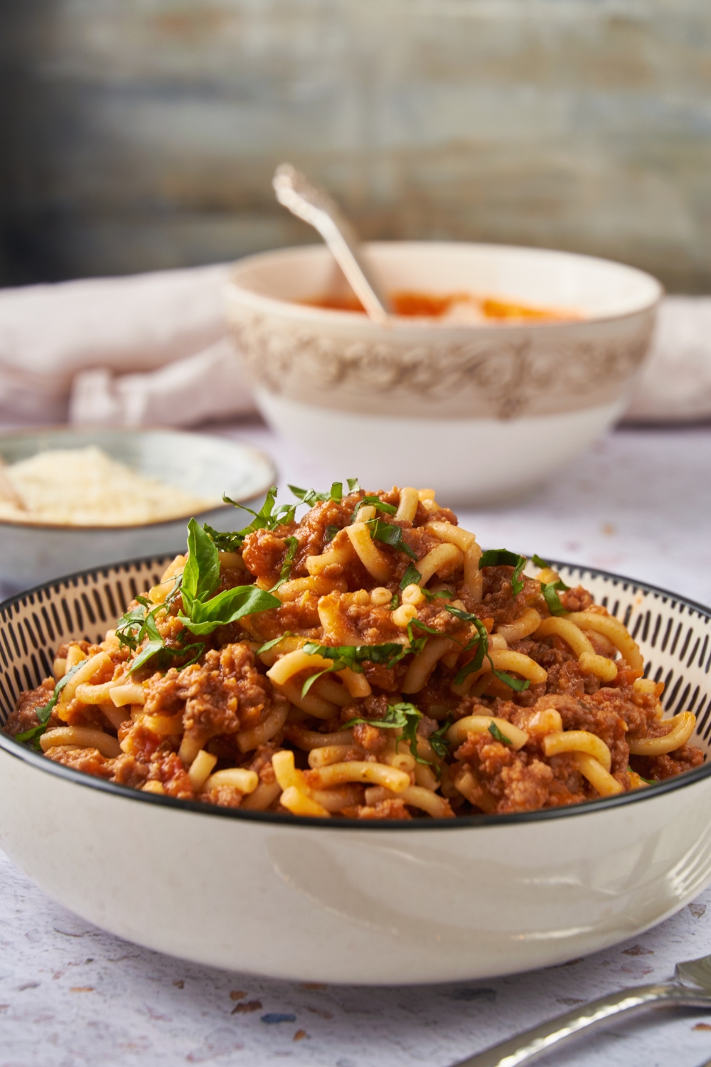 Beefaroni garnished with fresh green herbs and served in a decorative blue and white bowl.