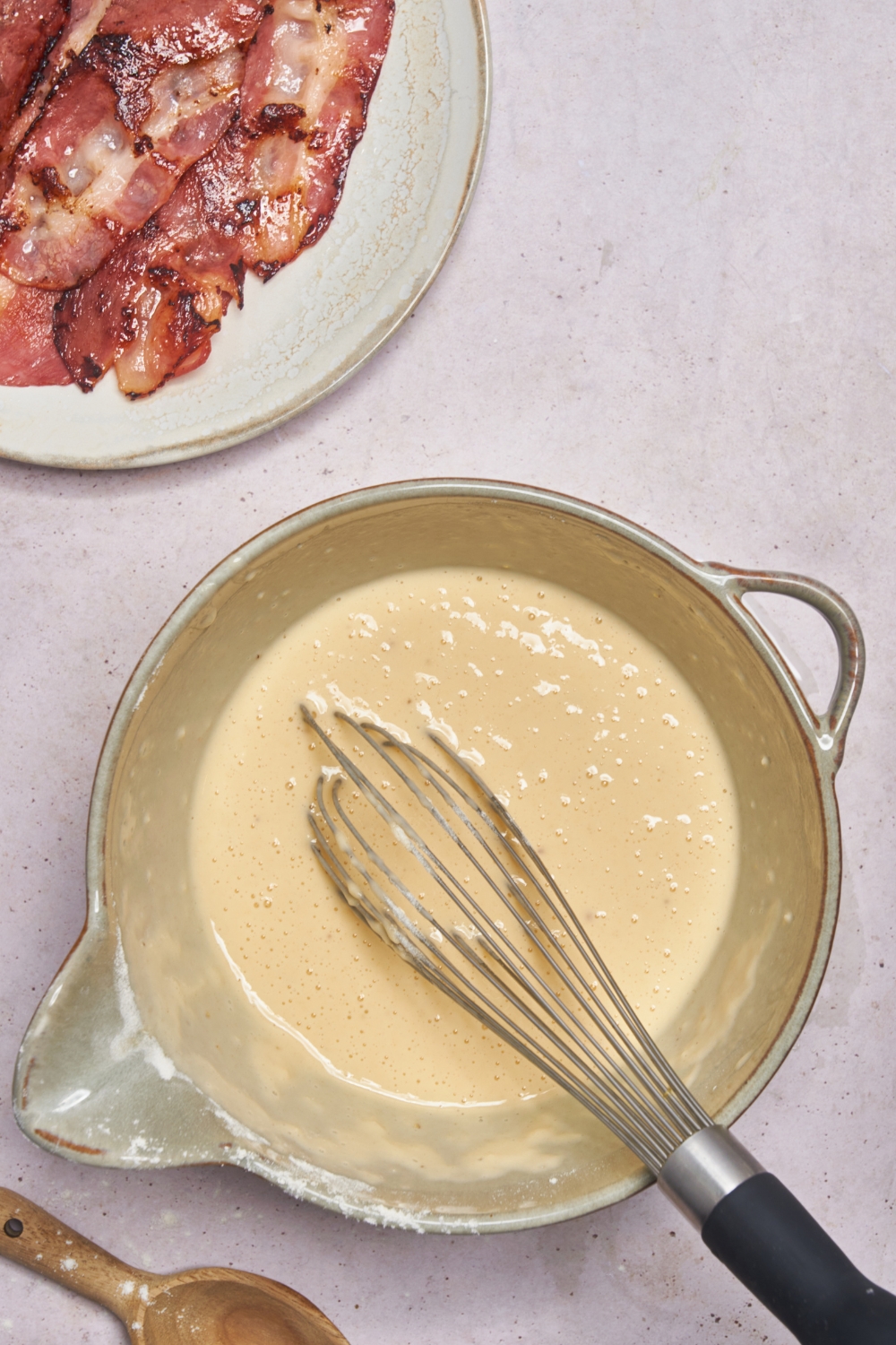 A mixing bowl with a smooth batter and a whisk in it.