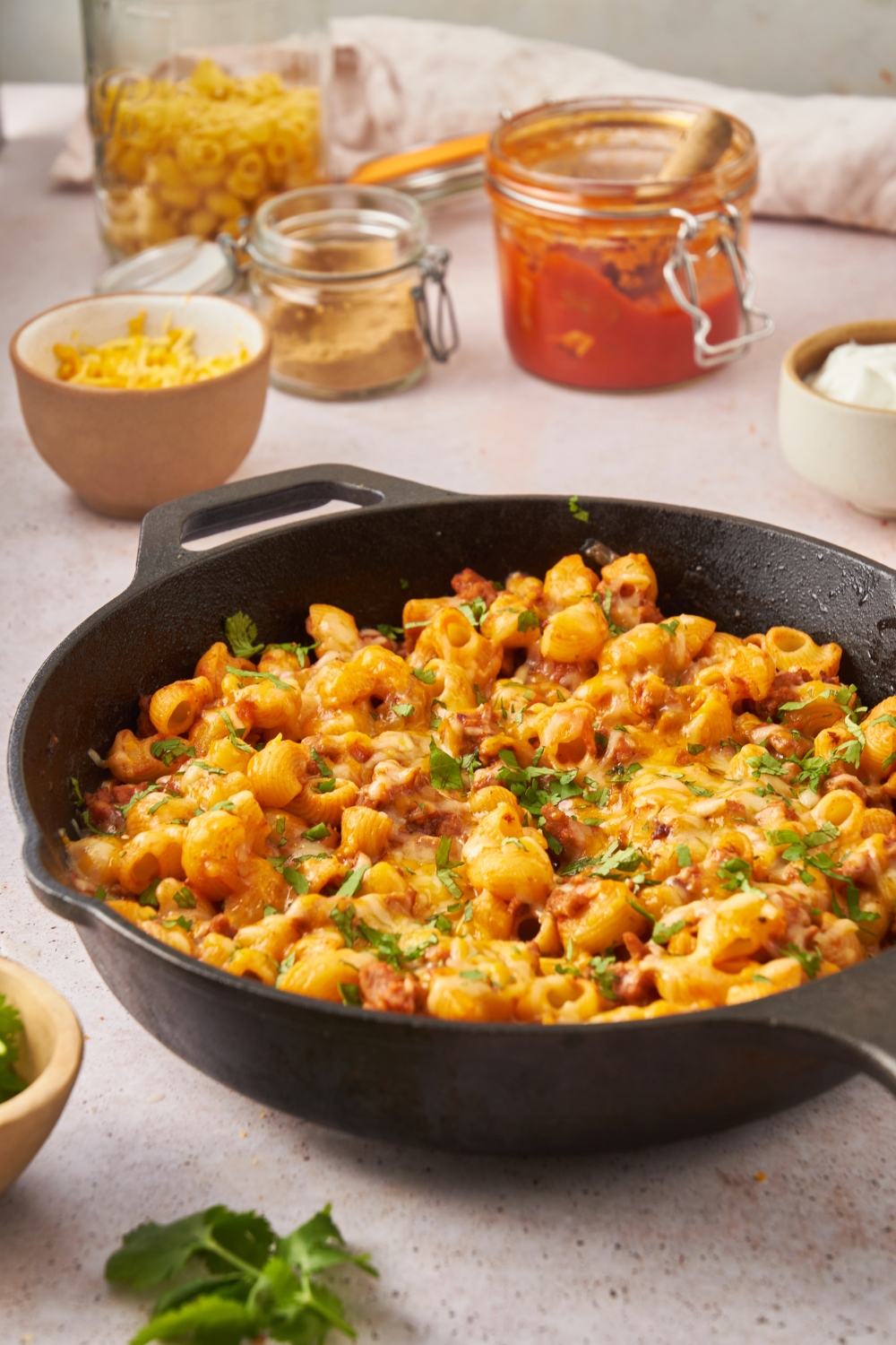 A black cast iron skillet with taco pasta casserole covered in melted cheese.