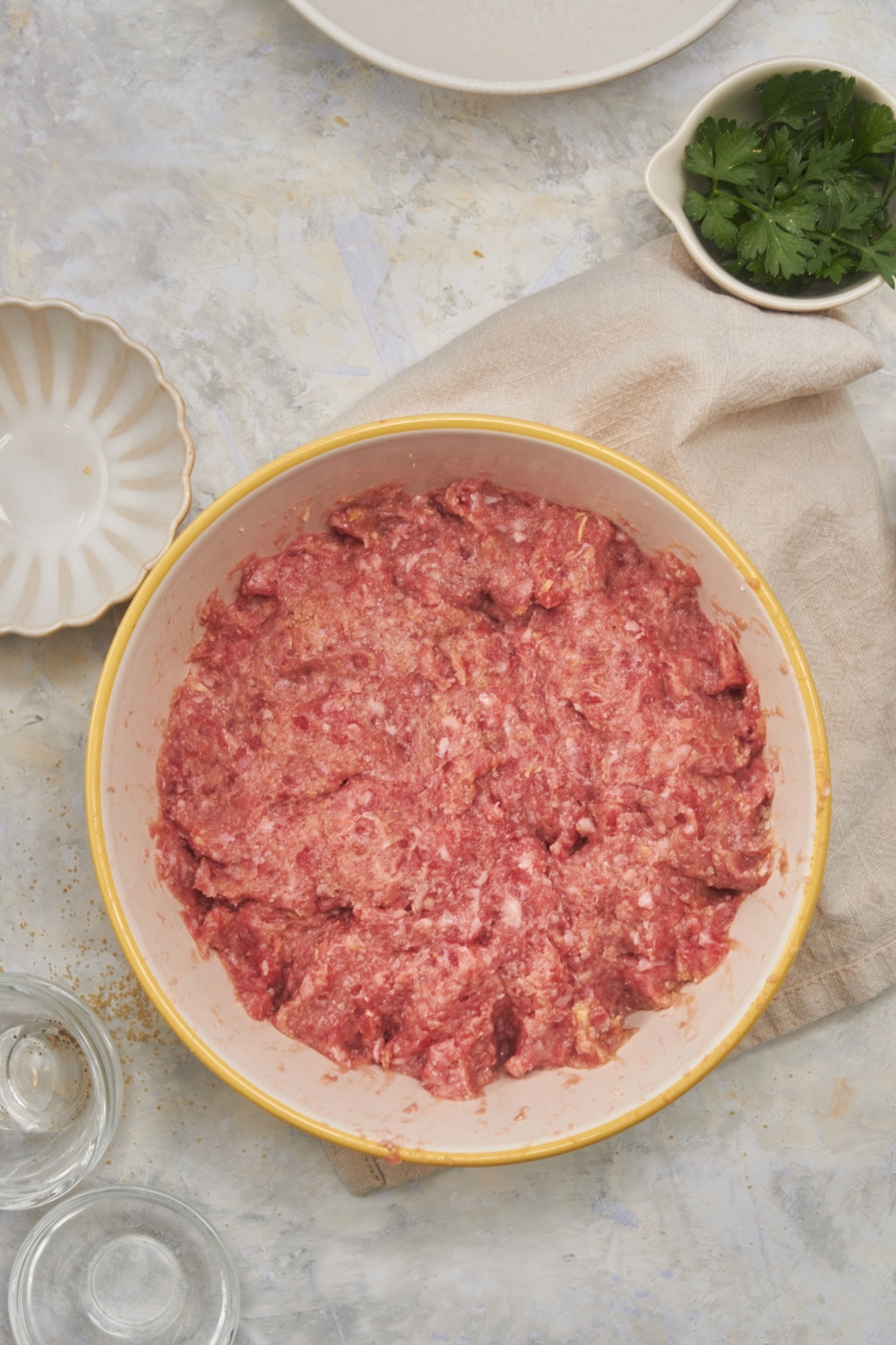 A white and yellow bowl filled with raw ground beef.