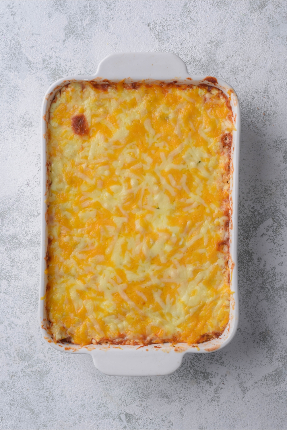 Overhead view of a freshly baked casserole covered in melted shredded cheese.