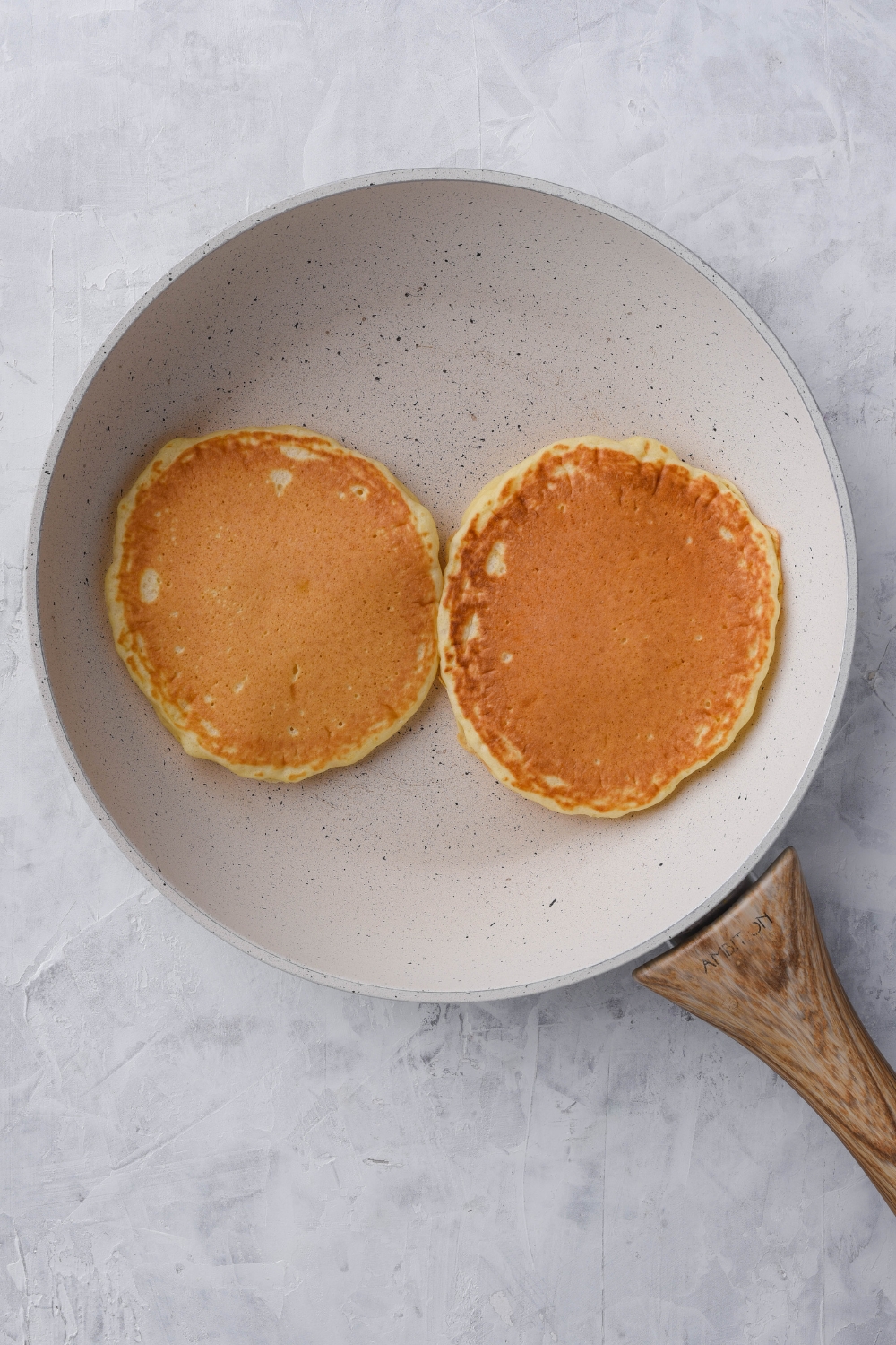 A skillet with two golden brown pancakes.