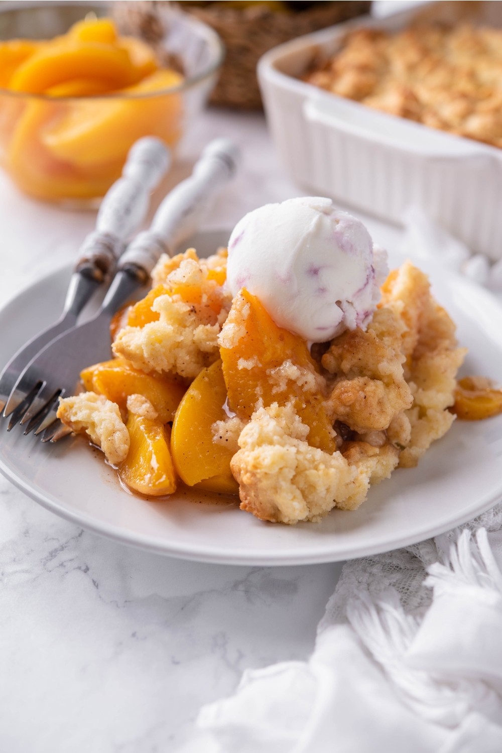 A plate with peach cobbler topped with a scoop of ice cream.