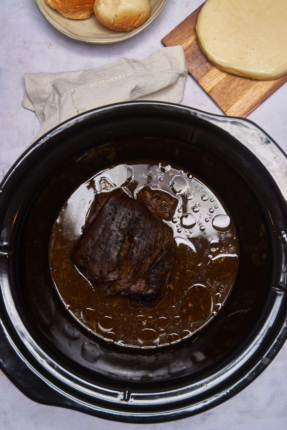 A black crockpot filled with cooked tri tip in a brown gravy.