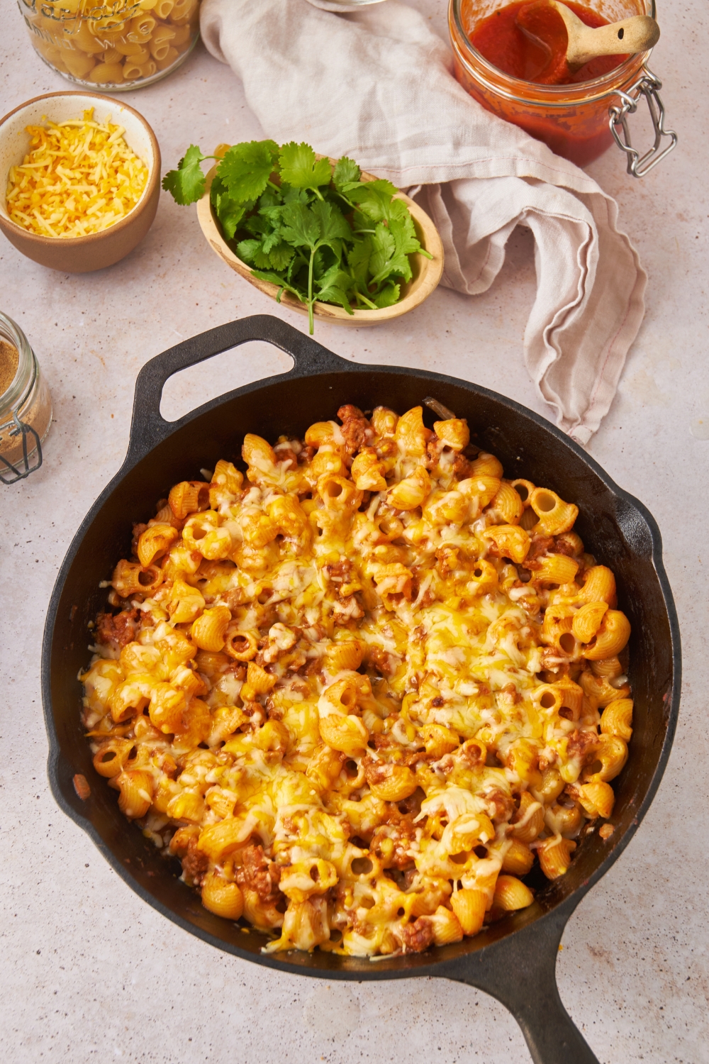 A black cast iron skillet with taco pasta casserole covered in melted cheese.