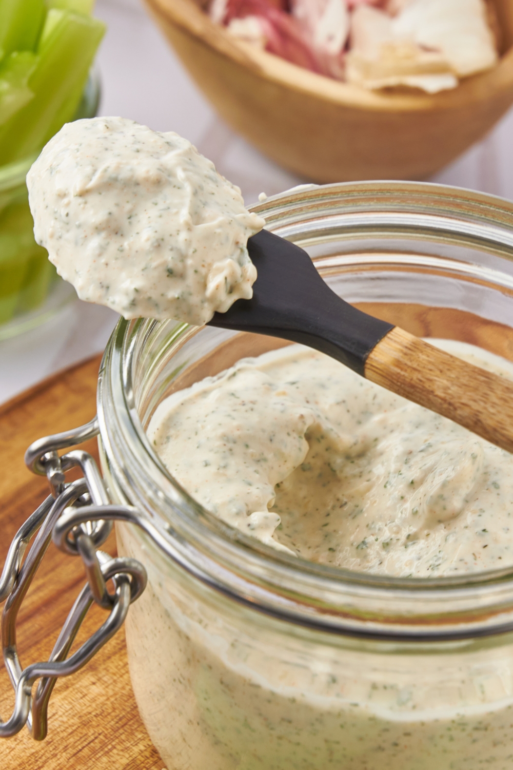 A mason jar with a small spatula dishing out ranch dip from it.