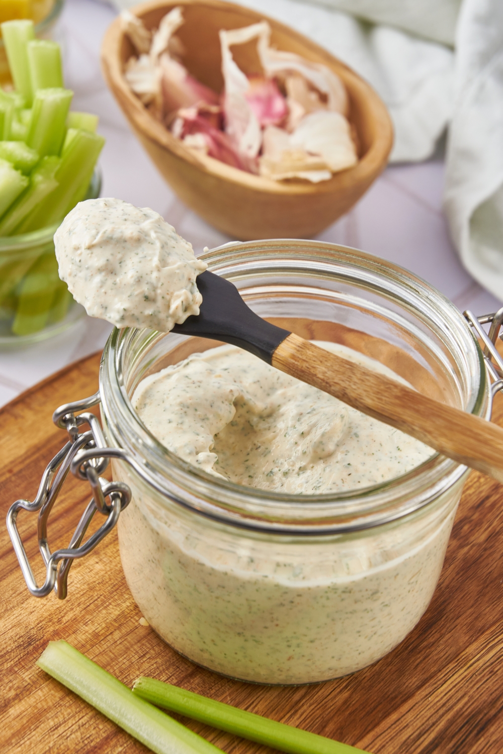 A mason jar with a small spatula dishing out ranch dip from it.