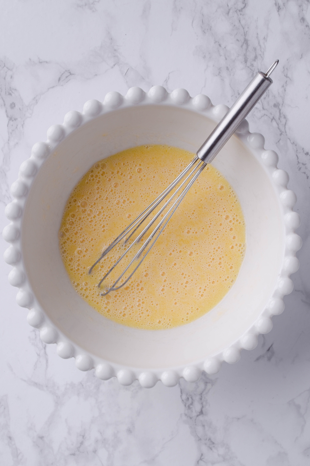 A mixing bowl with whisked egg mixture.