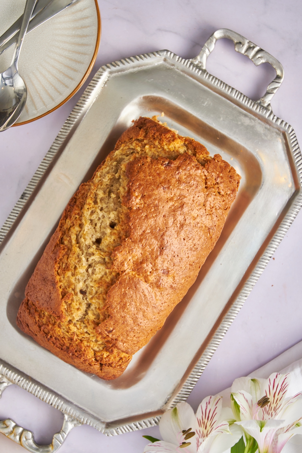 A serving tray with a loaf of banana bread on it.