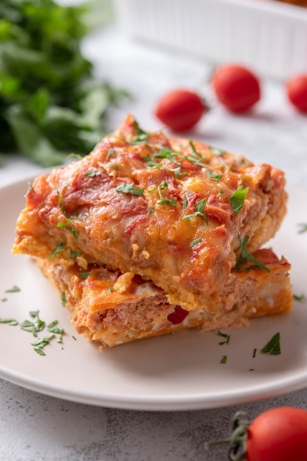 A plate with two squares of Mexican breakfast casserole garnished with fresh chopped cilantro.