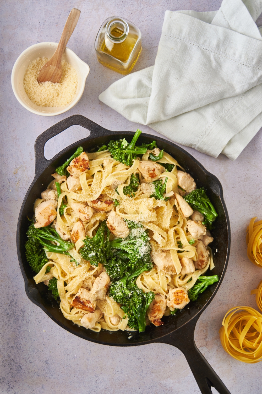 Chicken, broccoli, and fettuccine mixed with alfredo sauce in a skillet.