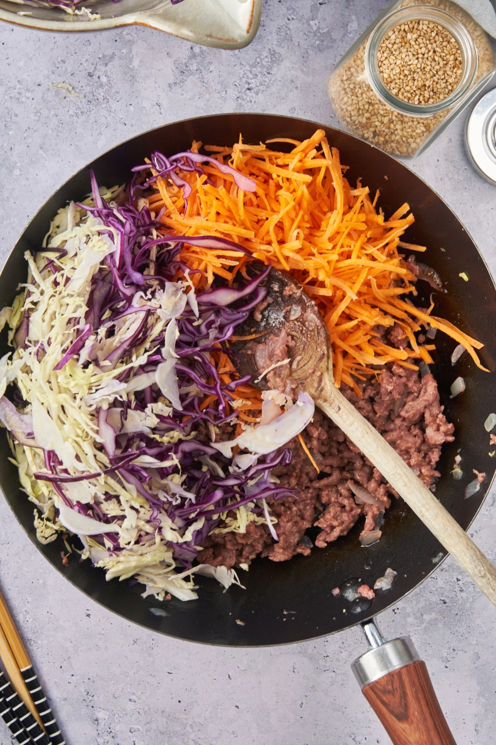 A skillet with the carrots and coleslaw mix added to the beef.