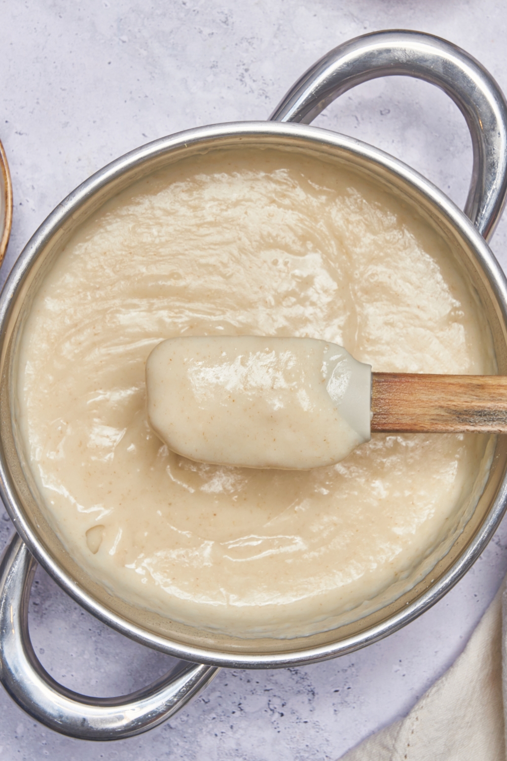 A pot with cooked cream of wheat. A rubber spatula is stirring the mixture.