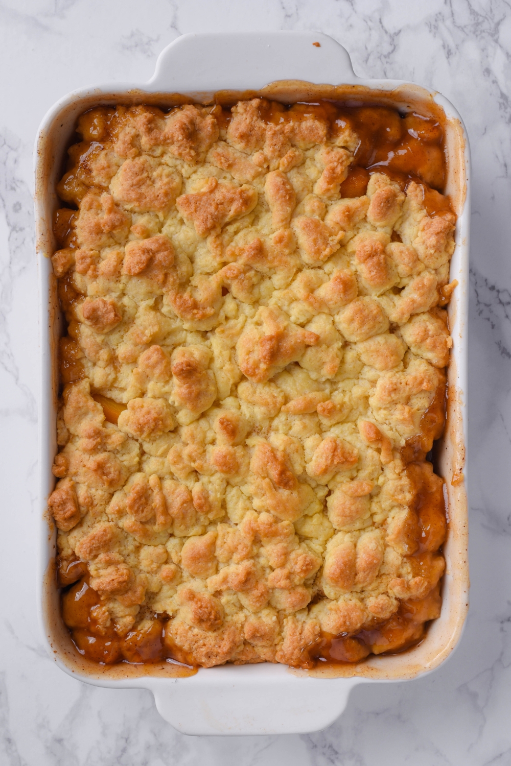 A baking dish with baked peach cobbler in it.