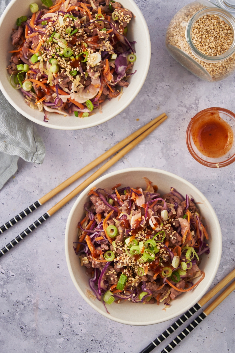 Two bowls with crack slaw and two sets of chop sticks.