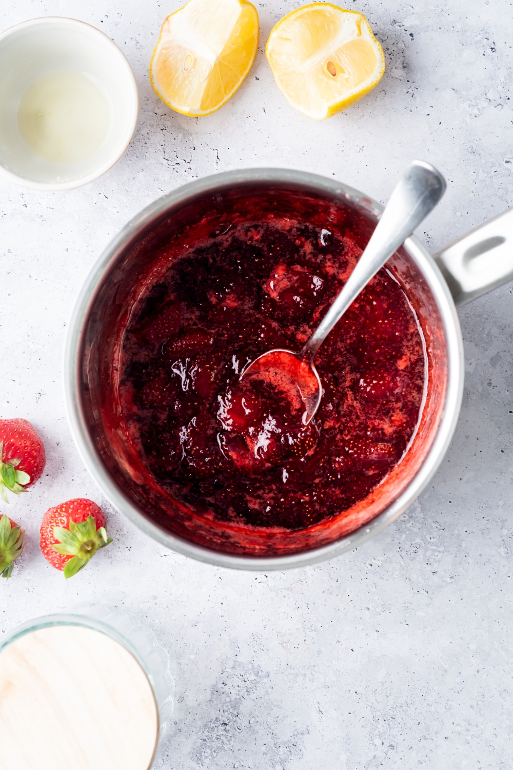 Strawberry compote in a pot with a spoon.