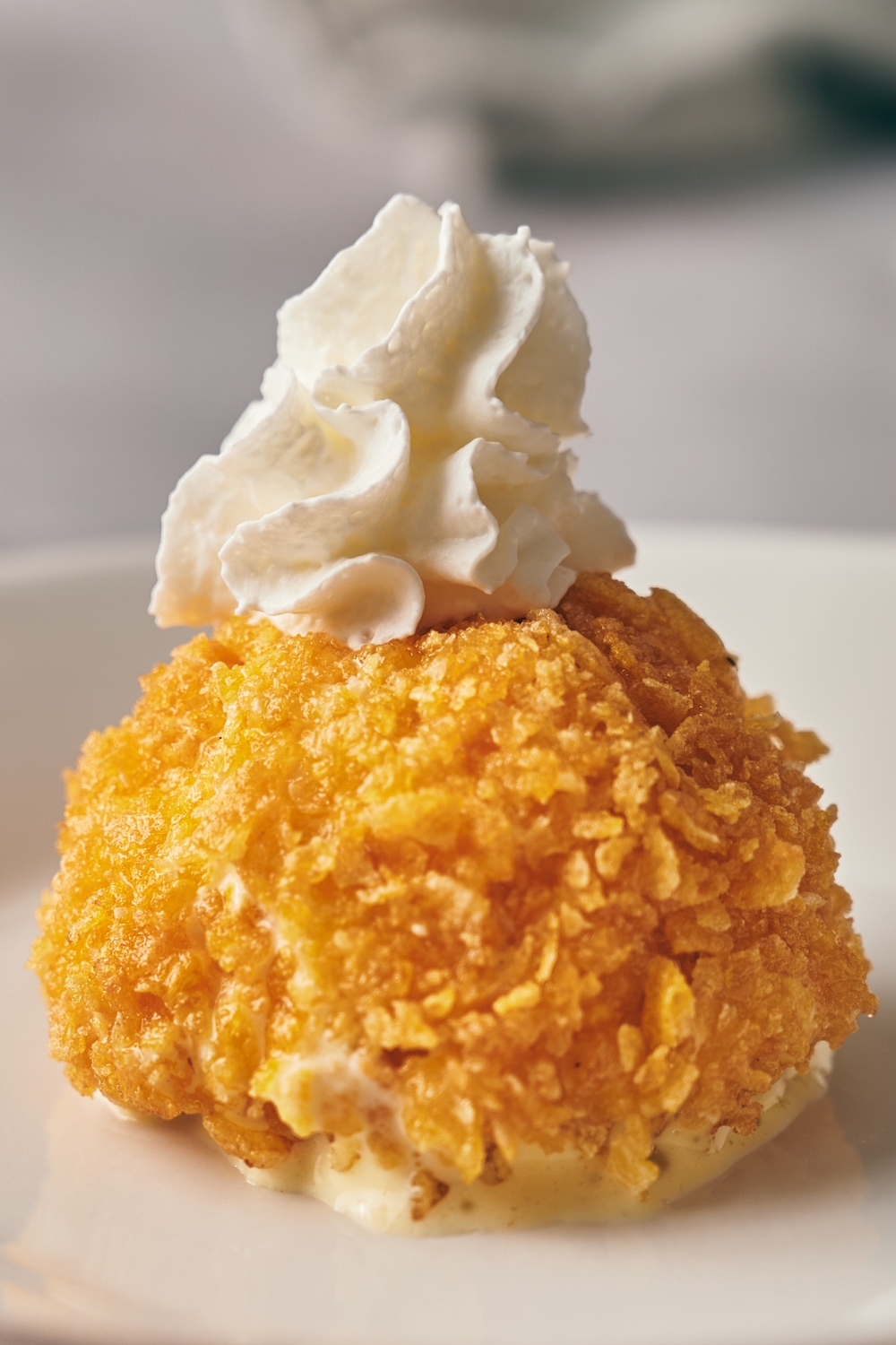 A plate with fried ice cream topped with whipped topping.